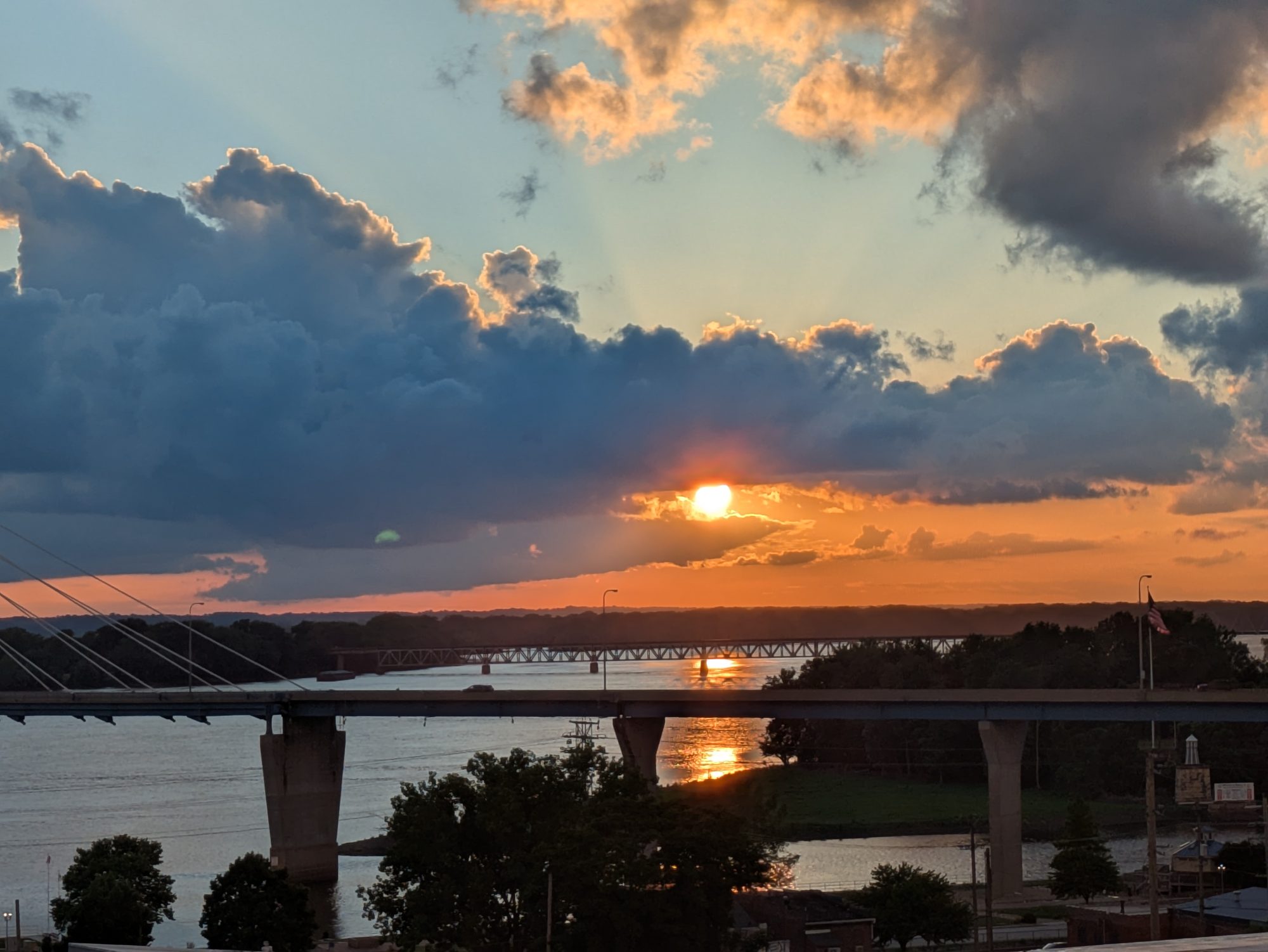 Sunset over the Mississippi River photographed from the terrace at 223 Hampshire, with the Bayview Bridge in front and an older truss bridge beyond.